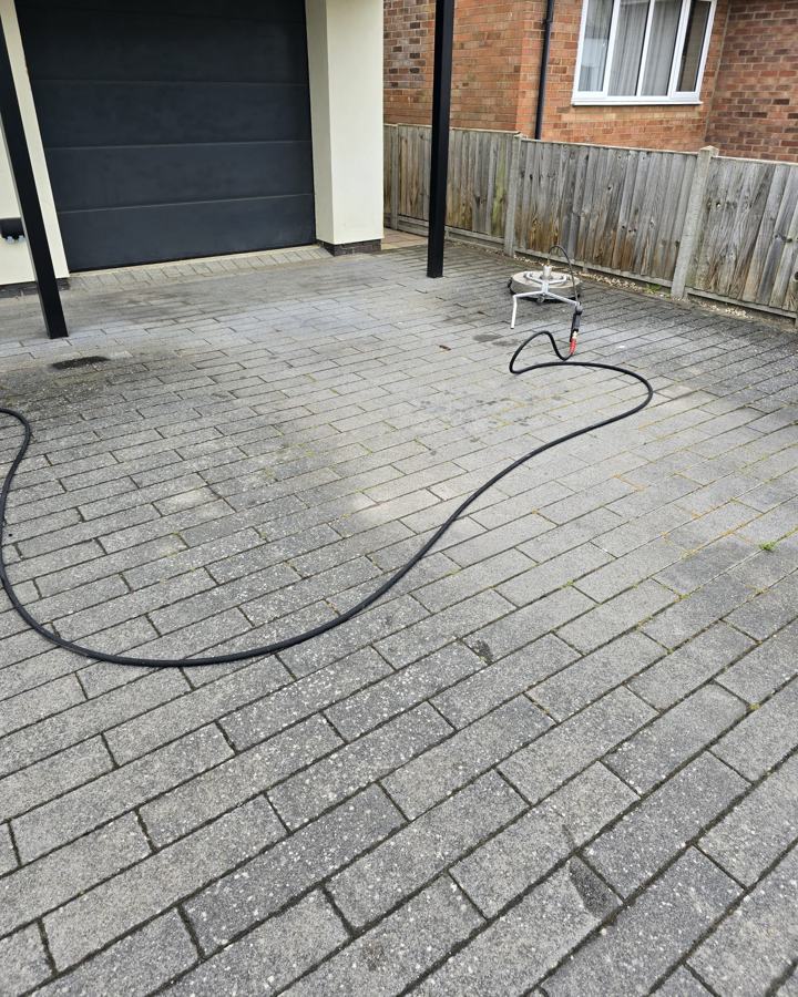 Grey driveway mid-clean with the surface cleaner, half done